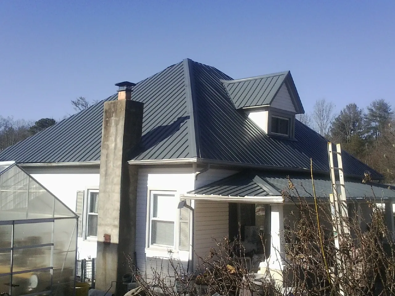 Dark blue standing seam metal roof on a white farmhouse with dormer — Slate & Tile Roof Repair by Roofing Brothers in Middle Point