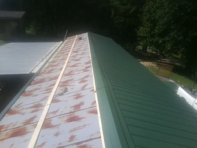 Old rusted panels beside newly installed green metal roofing — Wind Damage Roof Repair by Roofing Brothers in Middle Point