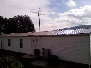 New metal roof on a single wide mobile home with a TV antenna in Middle Point