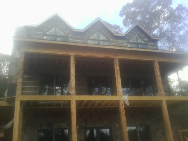 Dormers and porch framing on a large log home under construction — Roof Coating work by our crew in Middle Point