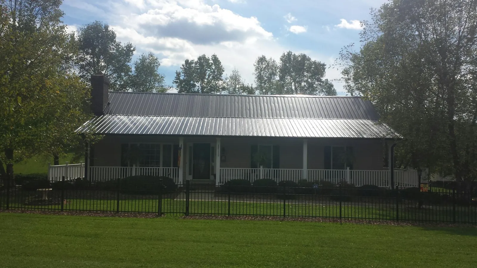 Gray metal roof on a brick ranch with a full width front porch — Gutter Guard Installation work by our crew in Middle Point
