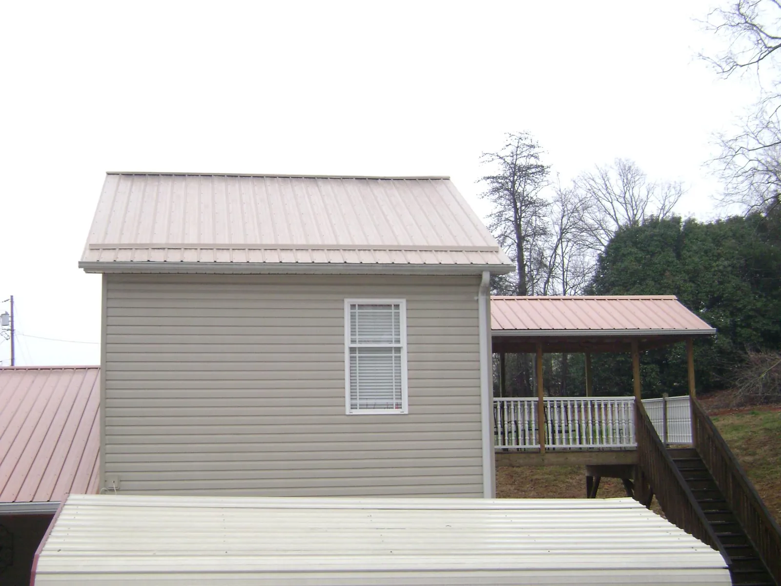 Tan metal roofs on a two story addition and attached porch, from a Roof Replacement job in Middle Point