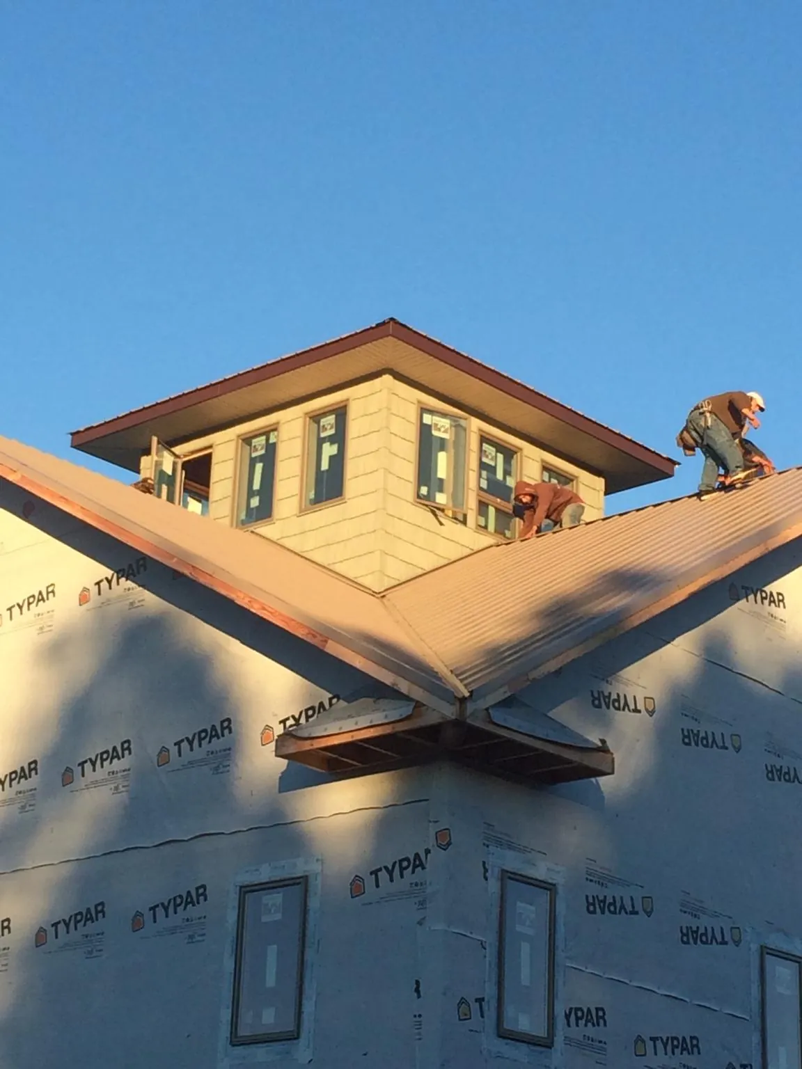 Roofers working around a rooftop cupola on a new metal roof at sunset — Roof Waterproofing in Middle Point by Roofing Brothers